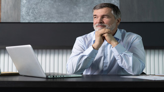 Image of a man sitting at a desk with a computer, reading about Autodesk's newly launched buying process.