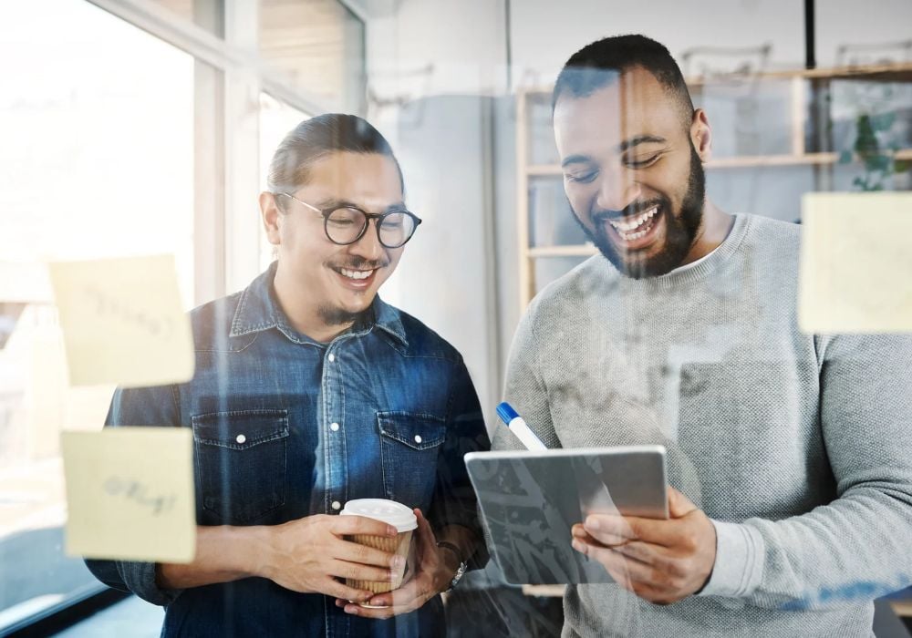 men smiling holding notepad